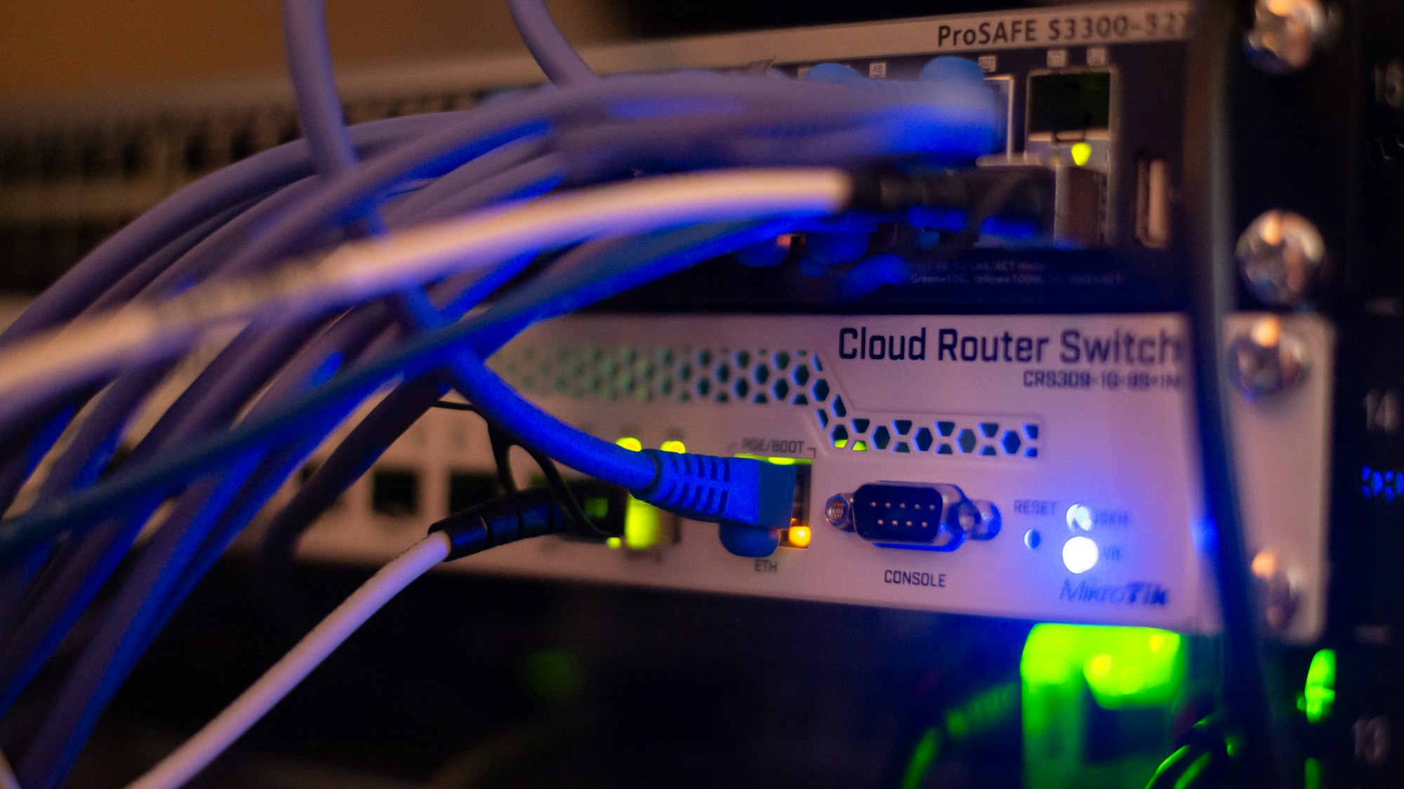 Close-up of a rack switch labelled Cloud Router Switch with blue patch cables looping into it